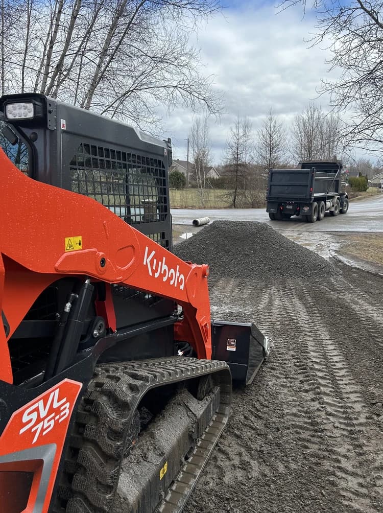 Chargeuse compacte Kubota SVL75-3 et pile de gravier sur un chantier.